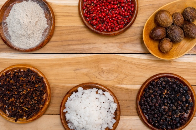 A set of spices on a wooden surface. Muscat salt cloves pepper on background