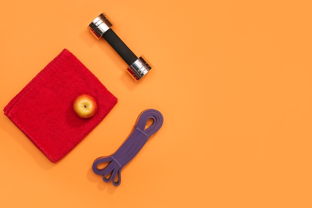 Set of sports accessories massage roller, resistance band, headphones on a yellow background