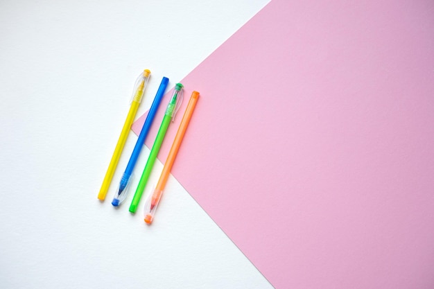 A set of stationery on a white and pink background pens of different colors