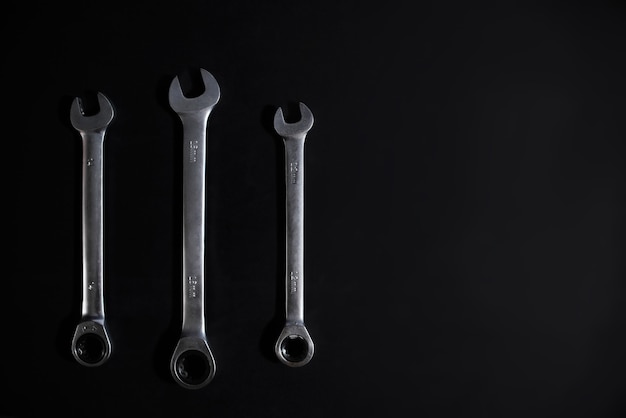 Set of steel combination wrench on a black background. Top view, copy space