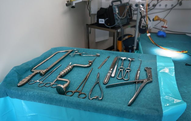 Set of steel surgical tools on blue cloth - real instruments used in mobile medical army tent, blurred operating table background
