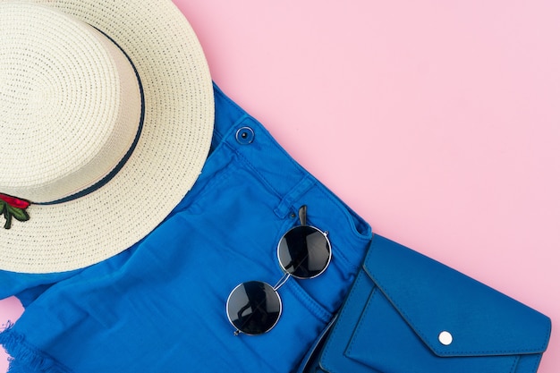 Set of summer clothes for woman on pink surface