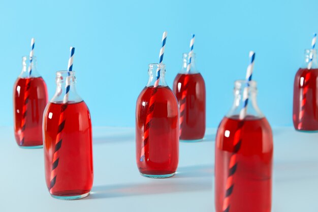 Набор летних коктейлей из клюквы со льдом в бутылках на синем фоне