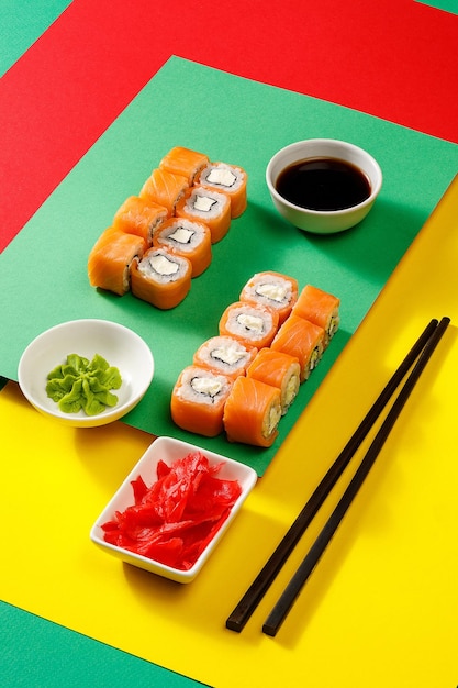 Set of sushi over colourful bright background served with soy sauce wasabi and gingerxA