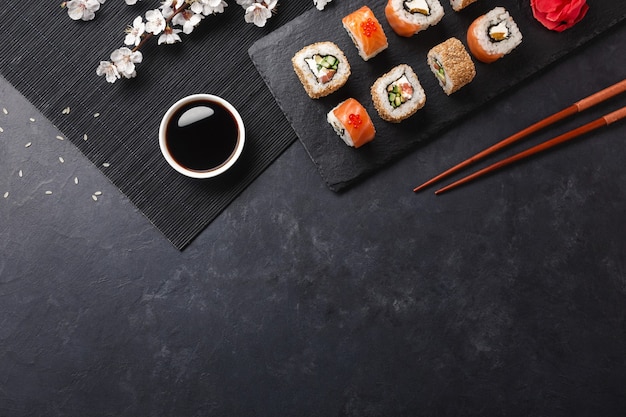 Set sushi en maki broodjes met tak van witte bloemen op stenen tafel. Bovenaanzicht.