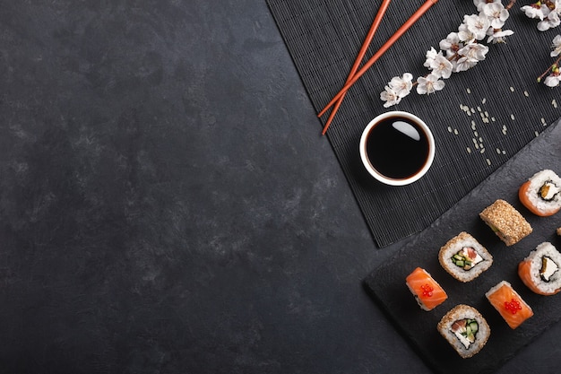 Set sushi en maki broodjes met tak van witte bloemen op stenen tafel. bovenaanzicht.