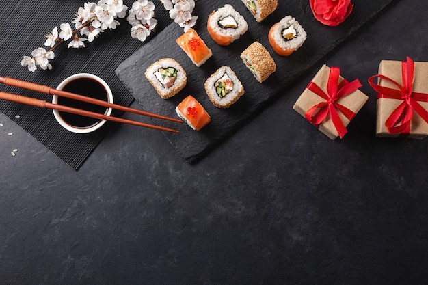 Set sushi, maki broodjes, geschenkdozen met tak van witte bloemen op stenen tafel bovenaanzicht.