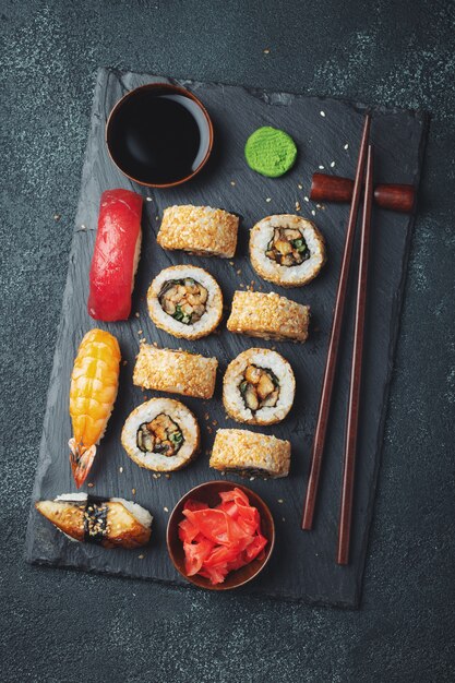 Set of sushi and maki on dark stone table.