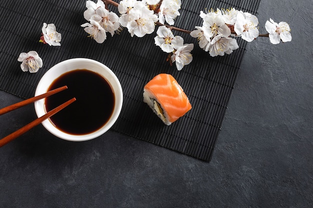 Set of sushi and maki rolls with branch of white flowers on stone table. Top view.