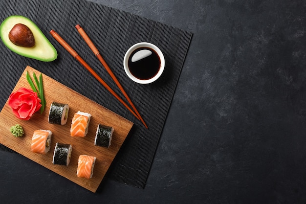 Set of sushi and maki rolls with sliced avocado on stone table. Top view.