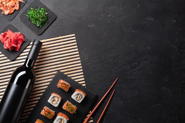 Set of sushi and maki with a bottle of wine on stone table. Top view with copy space.