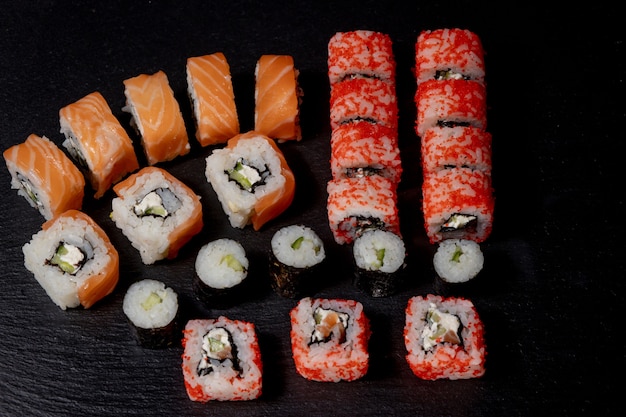 Insieme del rotolo di sushi sulla cucina cruda gastronomica sana fresca del wasabi tradizionale del pasto del cetriolo del riso di sushi del salmone giapponese del pesce dell'alimento dell'ardesia nera