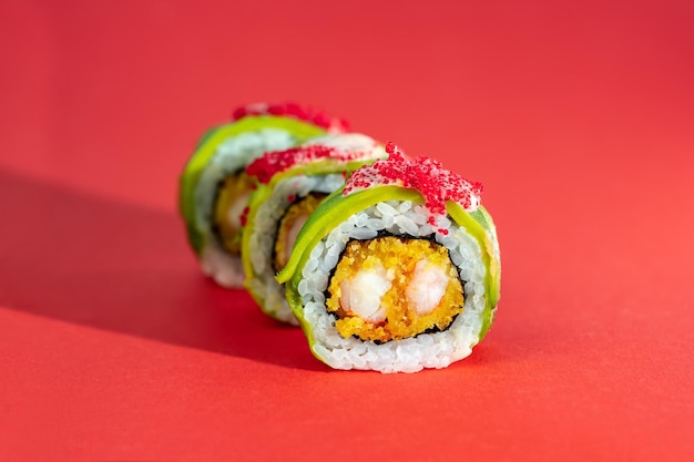 Set sushi roll met garnalen avocado en vliegende vis kaviaar op rode achtergrond Creatief beeld op kleur achtergrond met lange schaduw