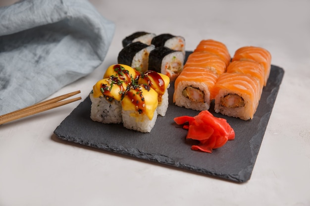 Set of sushi rolls on a black stone board. Grey surface