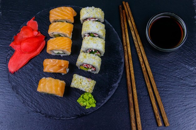 Set of sushi rolls on a black stone slate Top view