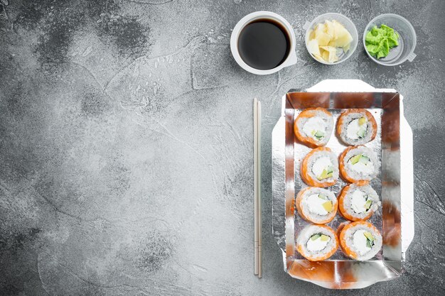 Set of sushi rolls in delivery food box set, on gray stone