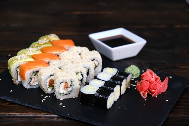 Set Sushi Rolls met tonijn, zalm, komkommer, avocado op een zwarte tafel. close-up, ondiepe scherptediepte. Assortiment van Japans eten in restaurant.