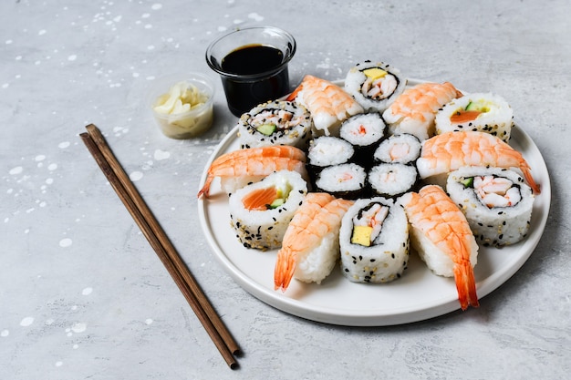 Set of sushi and rolls with salmon and shrimp on a gray table