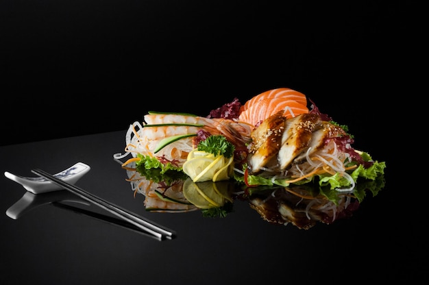 A set of sushi with shrimps and chopsticks on a black background with reflection