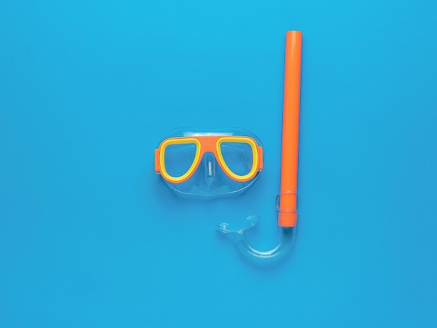 青い背景の水泳マスクとシュノーケルのセット夏のレクリエーションとスキューバダイビングの最小限の概念