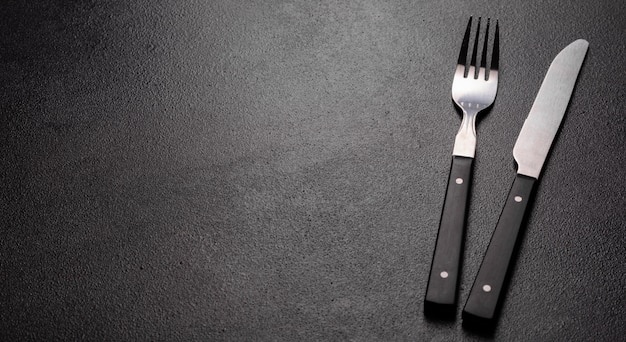 黒いコピースペースで食事の準備ができての食器のセット。金属製のナイフ、フォーク、スプーン、プレート