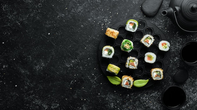 Set of tasty sushi and maki rolls on black stone background Japanese food Top view Free space for your text