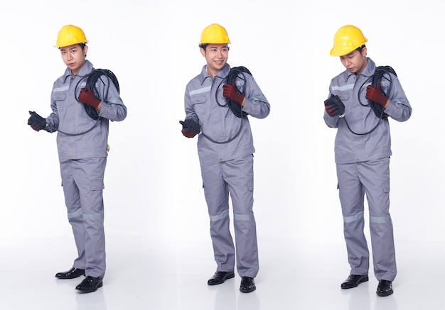 20代のアジア人男性の黒髪の3つのフルレングスのセットは、メカニックの衣装のドレスシューズを着用します。アクティブな男性は、白い背景に分離されたエンジニアとしてメンテナンス修理に電気ケーブルラインプラグを運ぶ