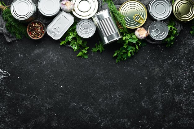 Set of tin cans with food on black stone background Food stocks Top view Free space for your text