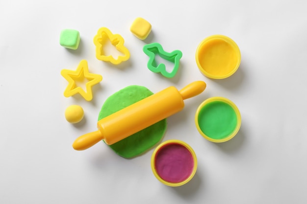 Set of tools and color play dough on white background top view