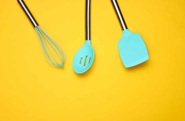 Set of tools for cooking on yellow. Silicone paddles with metal handles and whisk. Top view. Copy space.