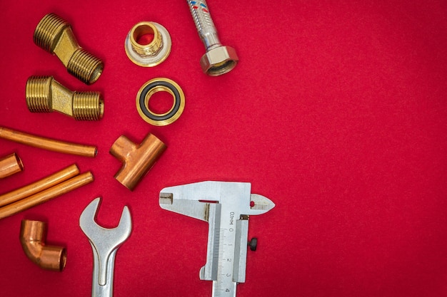 Set of tools and spare parts for plumbing on red background