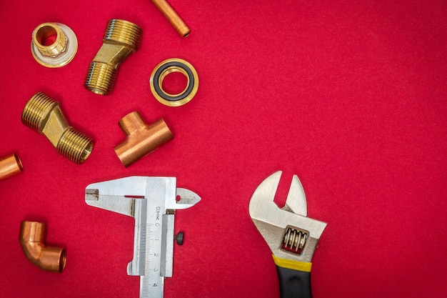 Set of tools and spare parts for plumbingon red background