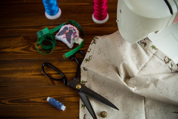 Photo a set of tools and threads for sewing clothes on a wooden background