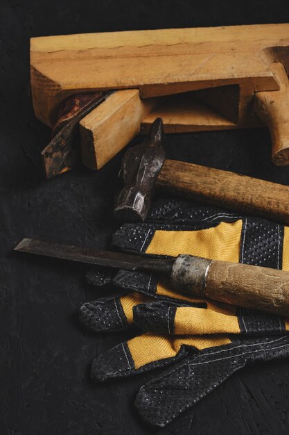 Set tools voor timmerlieden hamer beitel en vliegtuig met handschoenen donkere houten achtergrond