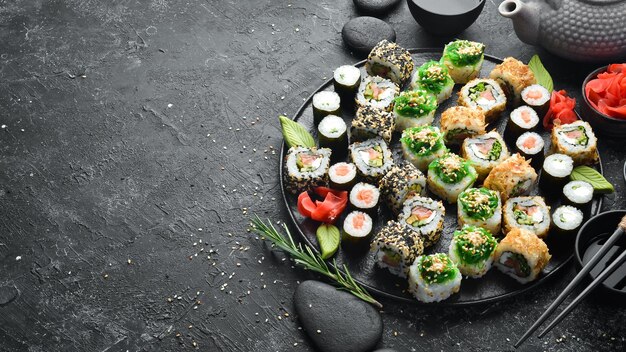 Set of traditional sushi on a black plate Sushi and rolls on a dark background