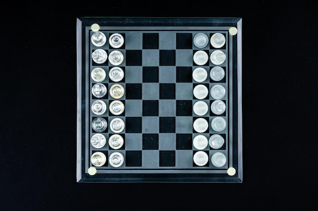 Set of transparent glass chess pieces over black selective focus copy space view from above