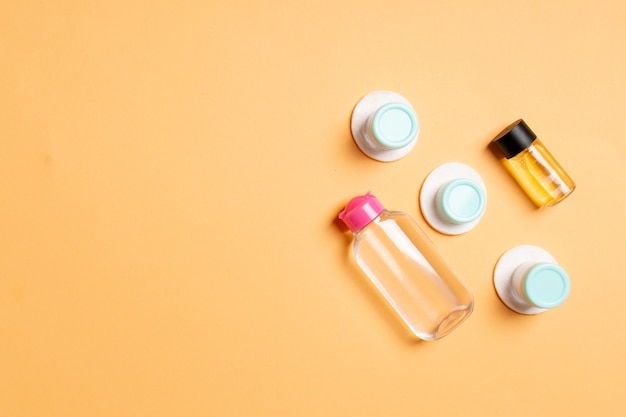 Set of travel size cosmetic bottles on yellow background