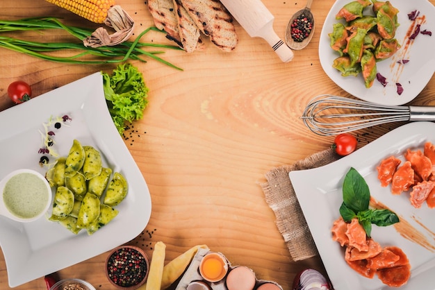 Set of Ukrainian cuisine Vareniks fresh vegetables spices Top view On a wooden background Copy space