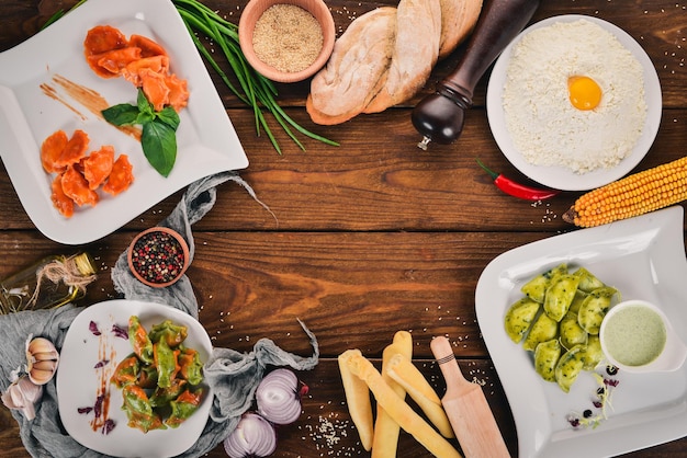 Set of Ukrainian cuisine Vareniks fresh vegetables spices Top view On a wooden background Copy space