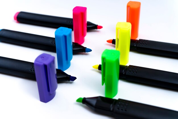 Set of uncovered color-ordered highlighters facing each other on white background. Perspective view