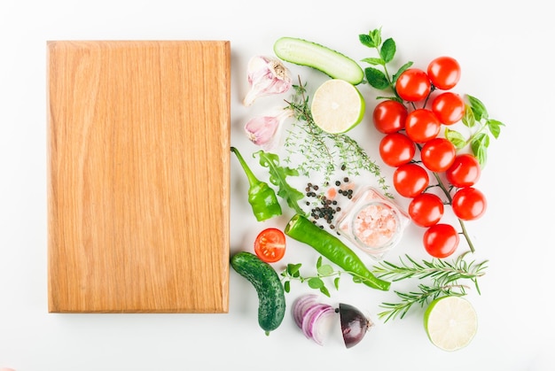 set of universal vegetables and spices on a white background with a wooden board place for a recipe