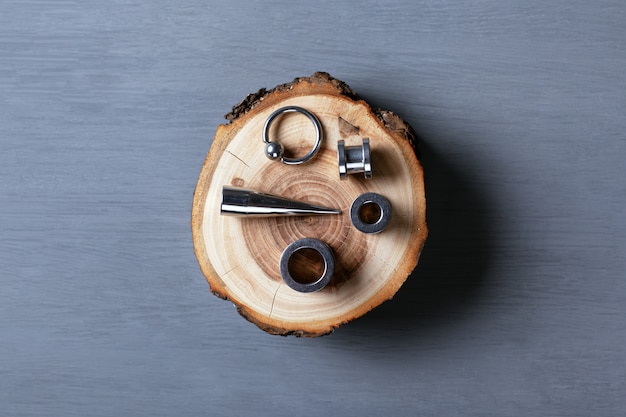 A set of unusual earrings and stretch marks for piercing on a piece of wood.