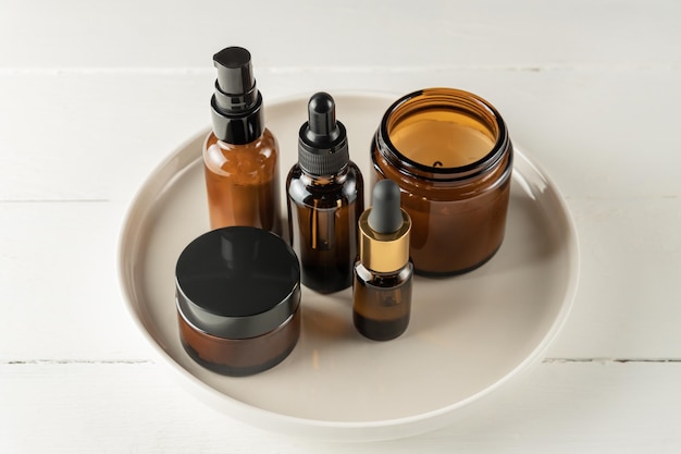 Set van amberkleurige cosmetische flessen van glas op een bord op houten ondergrond. Merkloos verpakkingsontwerp voor natuurlijke cosmetica.