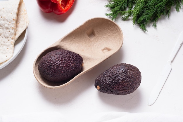 Set van avocado in kartonnen verpakking op houten tafel