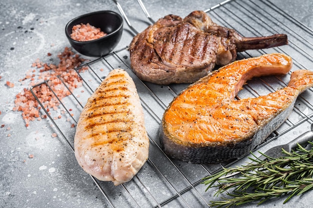 Set van bbq gegrild vlees steaks zalm rundvlees en kalkoen op een grill grijze achtergrond bovenaanzicht