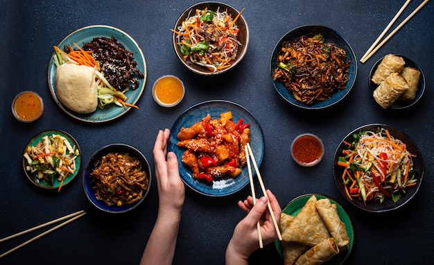 Set van chinese gerechten op tafel vrouwelijke handen met eetstokjes