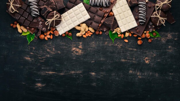 Set van chocolade met noten, koekjes en cacao Op een zwarte houten achtergrond Bovenaanzicht Kopieer ruimte voor tekst