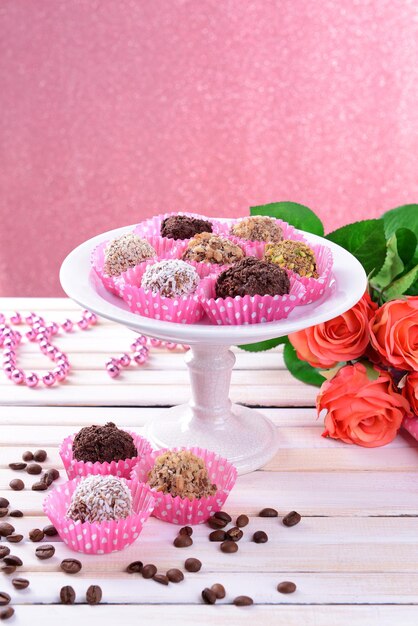 Set van chocolade snoepjes op tafel op roze achtergrond