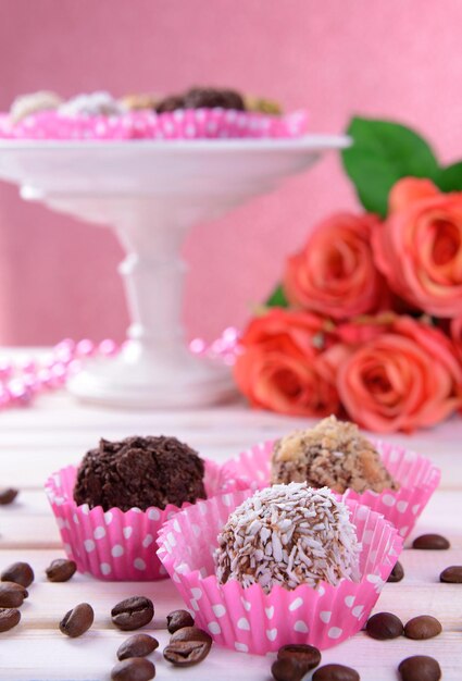 Set van chocolade snoepjes op tafel op roze achtergrond