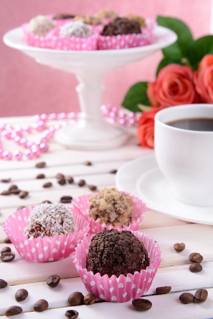 Set van chocolade snoepjes op tafel op roze achtergrond